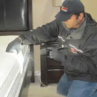 Bed bug inspection technician checking a mattress and bed frame for signs of infestation in Bakersfield, CA
