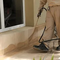 General pest control technician spraying exterior perimeter around a home in Bakersfield, CA