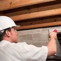 Termite inspection technician checking a basement wall and framing for termite activity in Bakersfield, CA