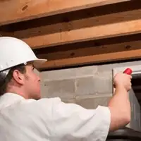 Termite inspection technician checking a basement wall and framing for termite activity in Bakersfield, CA